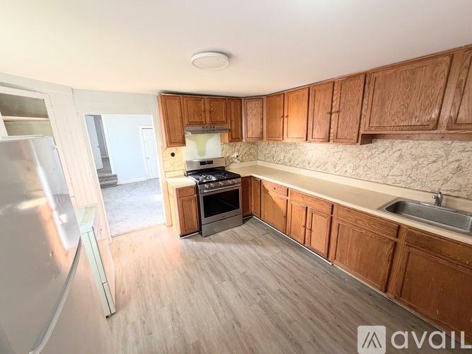 A kitchen with wooden cabinets and a marble backsplash.