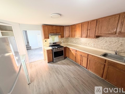 A kitchen with wooden cabinets and a marble backsplash.