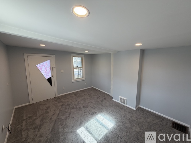 A room with a carpeted floor and a window with a view of a building outside.
