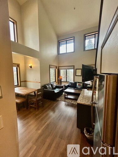 A living room with a black couch and a wooden floor.
