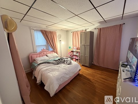 A bedroom with a bed, a wardrobe, and a window with curtains.