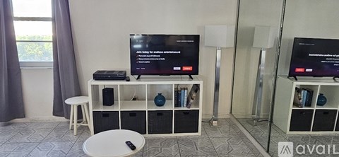 A living room with a television on a stand and a remote control on the floor.