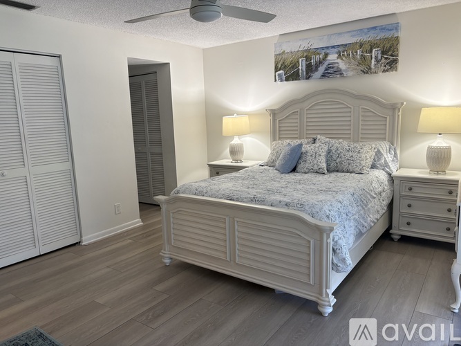 A bedroom with a large bed, a dresser, and a painting on the wall.