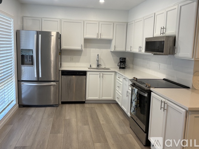 A kitchen with white cabinets and a stainless steel refrigerator.