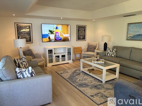 A living room with a grey couch, a white coffee table, and a television on the wall.
