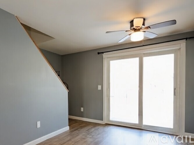A room with a ceiling fan and sliding glass doors.