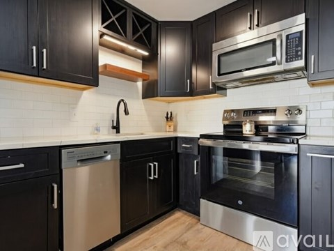 A kitchen with black cabinets and stainless steel appliances.
