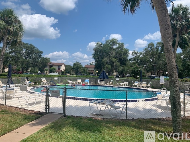A pool surrounded by a fence and chairs.