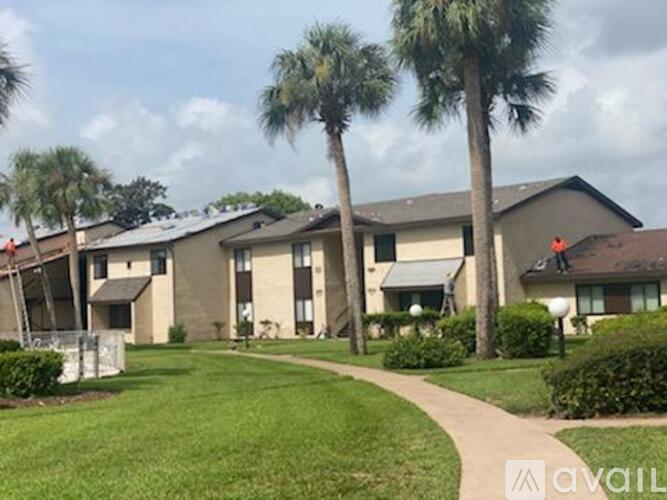 Apartment complex with a grassy area and palm trees.