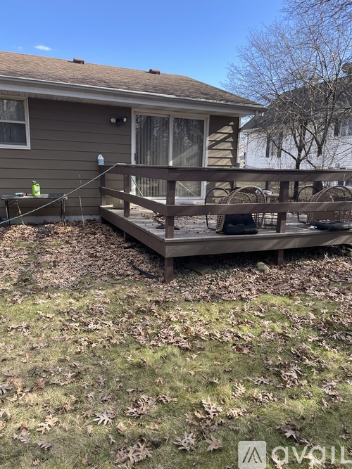 A house with a deck and a tree in the background.