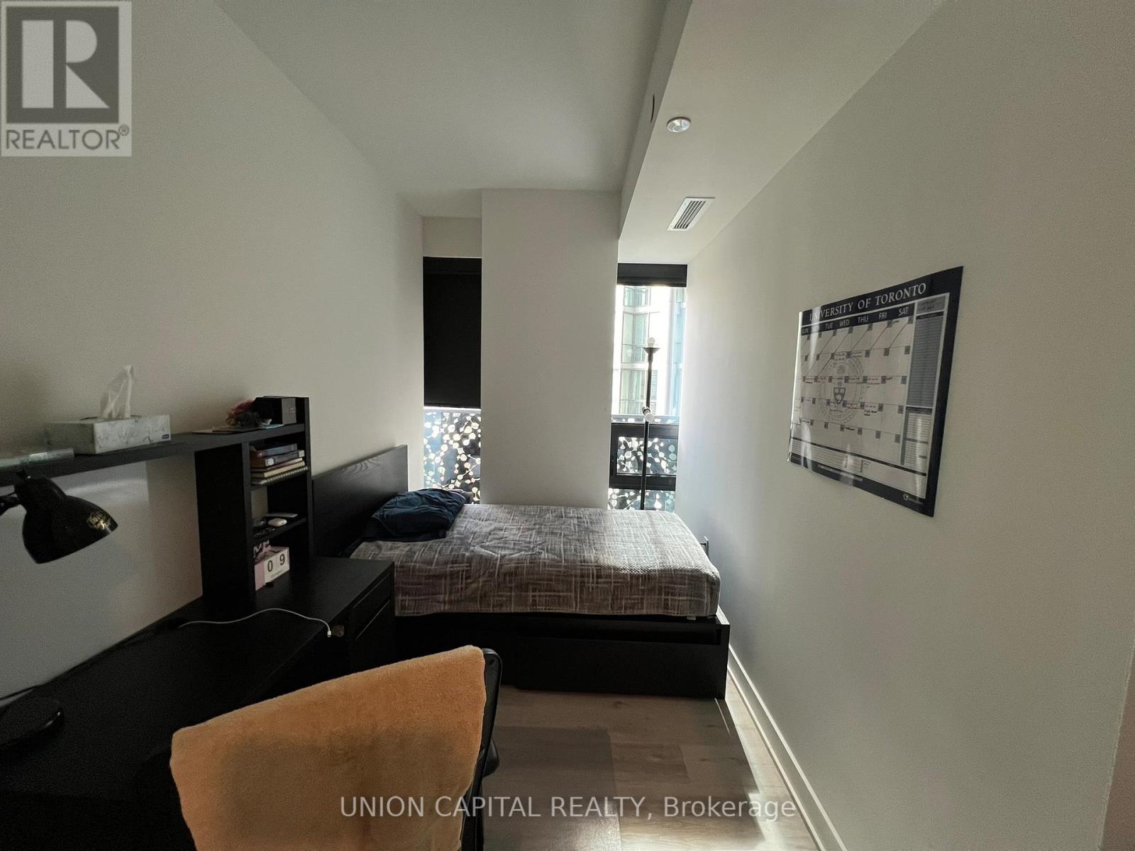 A bedroom with a bed, desk, and chair.