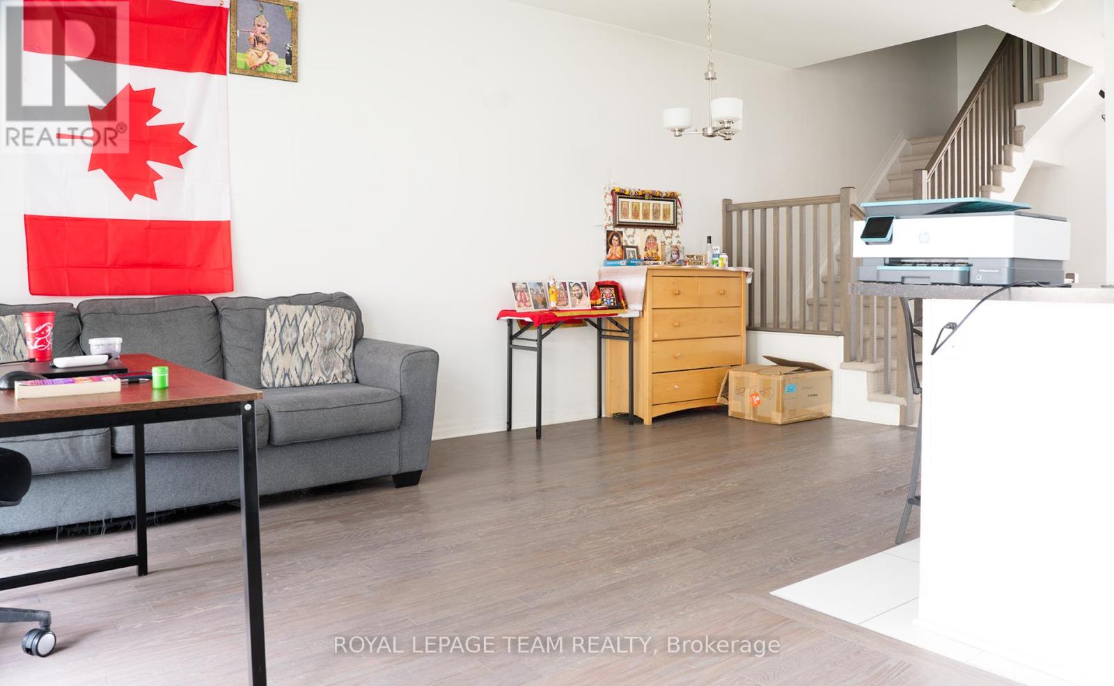 A living room with a grey couch, a coffee table, and a printer on the desk.