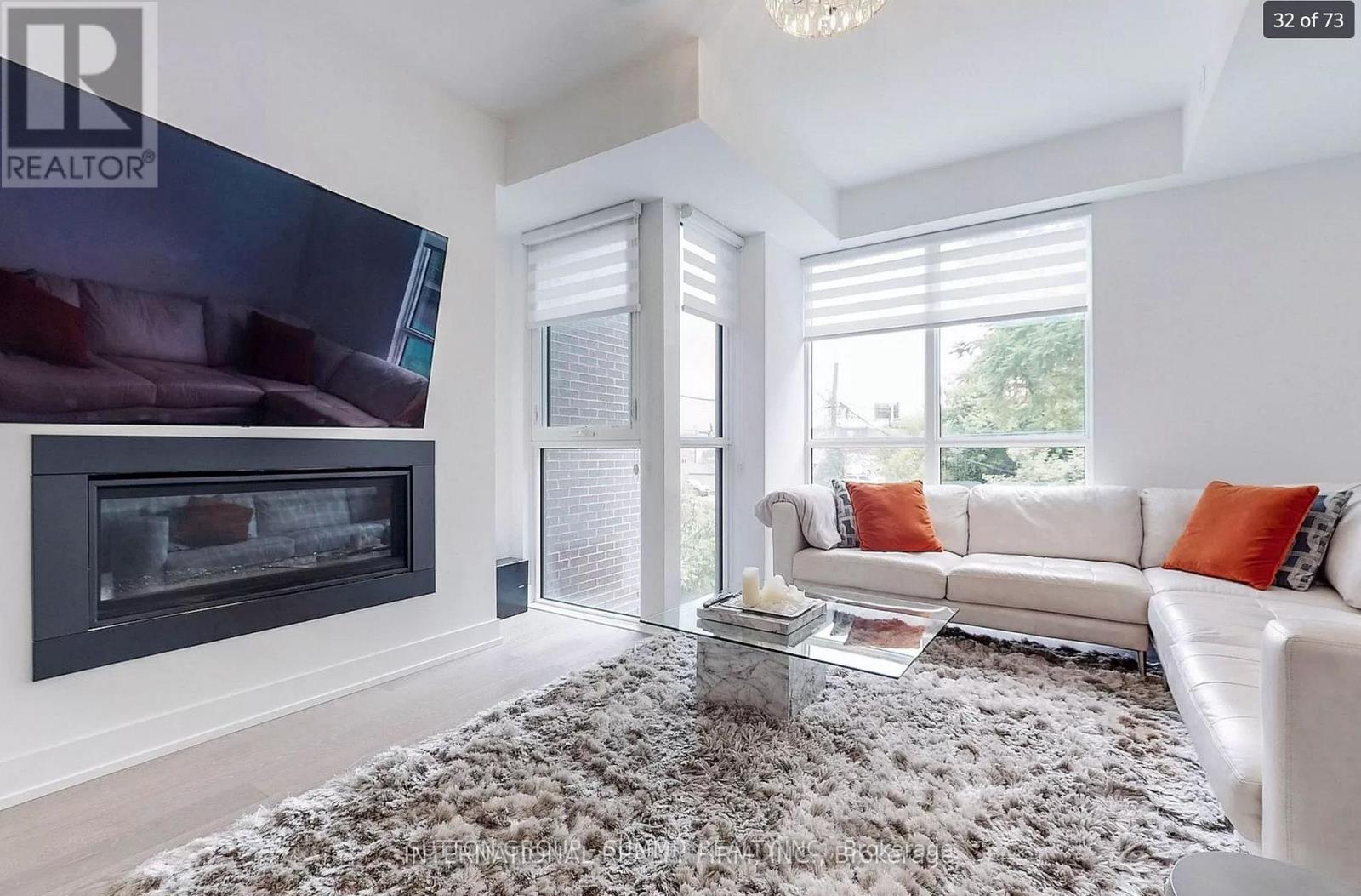 A living room with a grey rug, a white couch, and a fireplace.