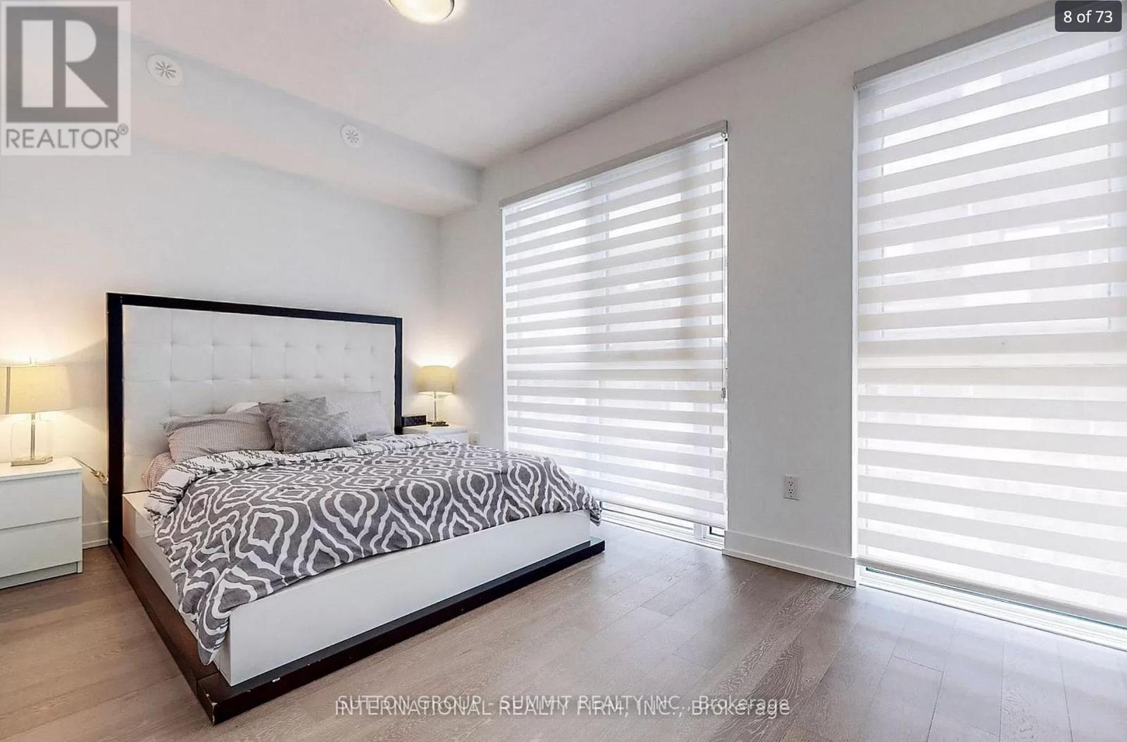 A bedroom with a large bed and a window with blinds.