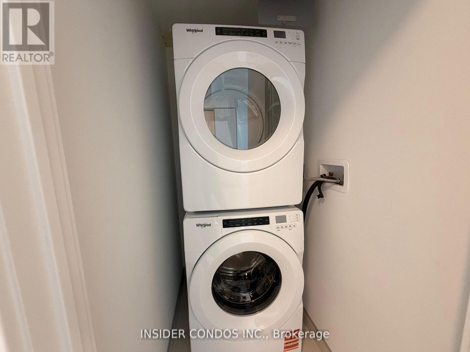 A white washing machine and dryer are stacked on top of each other in a small space.