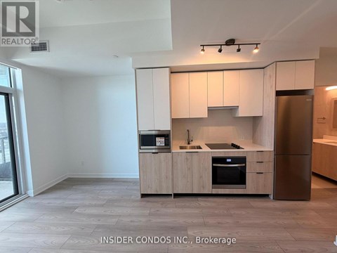 A kitchen with white cabinets and a refrigerator.