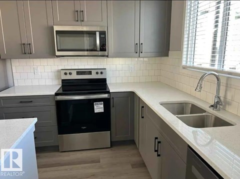 A kitchen with a stove, microwave, and sink.