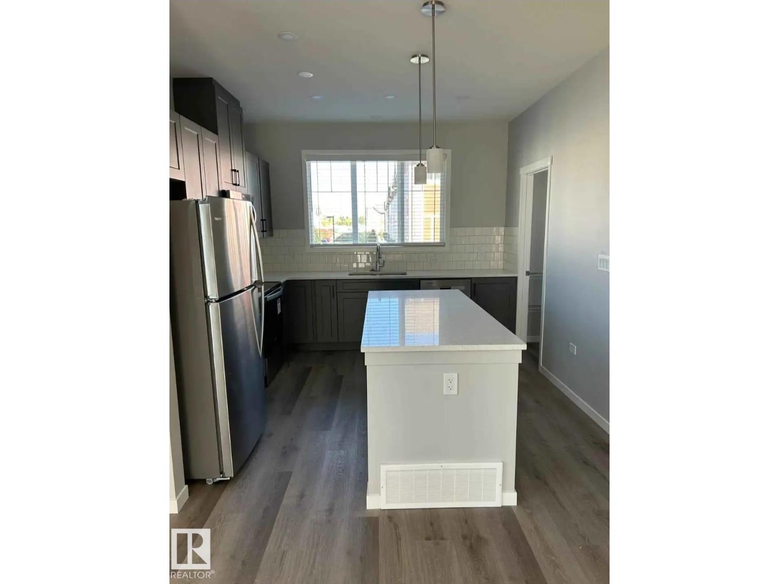 A kitchen with a refrigerator, cabinets, and a countertop.