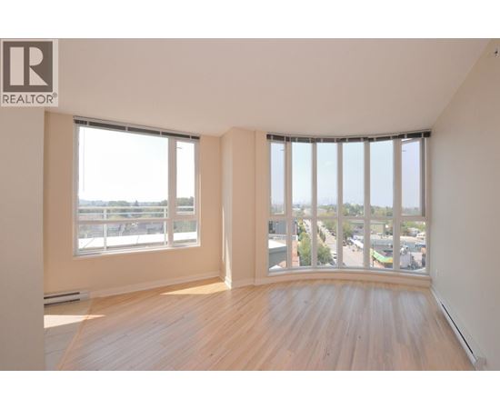 A large empty room with a view of the city through the windows.