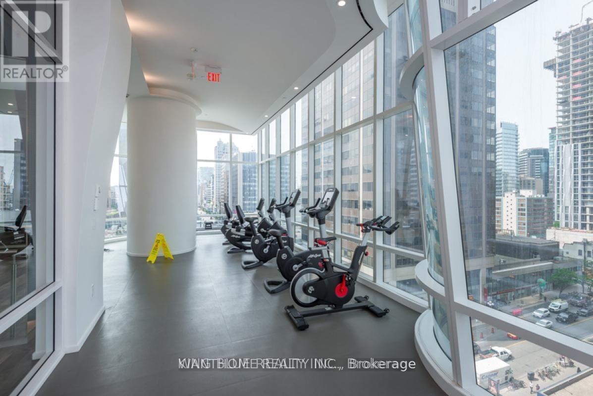 A gym with a row of stationary bikes and a view of the city outside the windows.