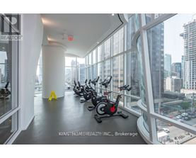 A gym with a row of stationary bikes and a view of the city outside the windows.