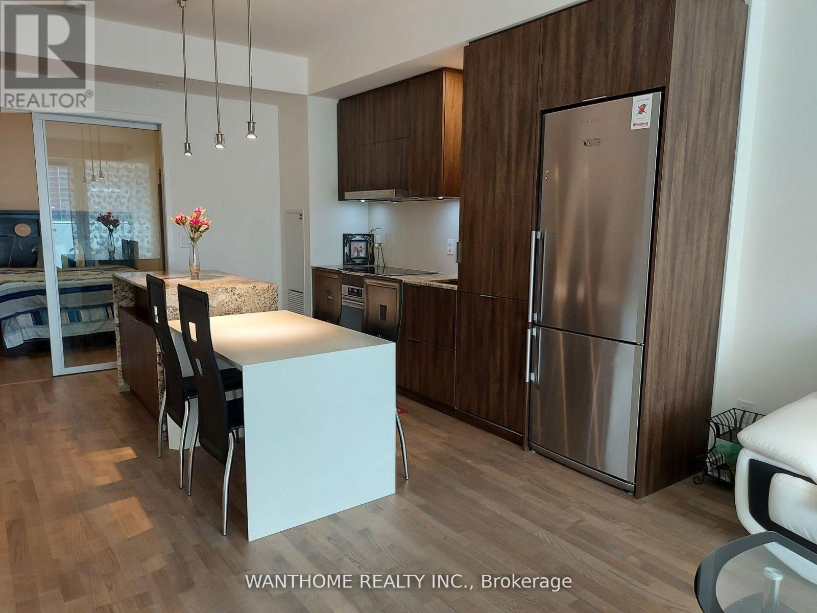 A kitchen with a refrigerator, sink, and table.