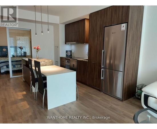 A kitchen with a refrigerator, sink, and table.