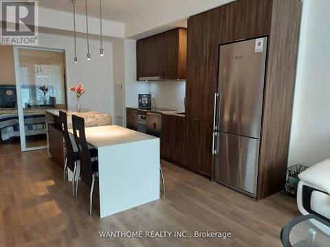 A kitchen with a refrigerator, sink, and table.