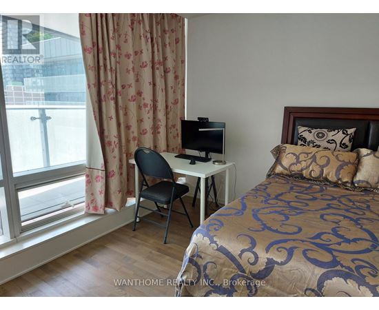 A bedroom with a bed, desk, chair, and window.