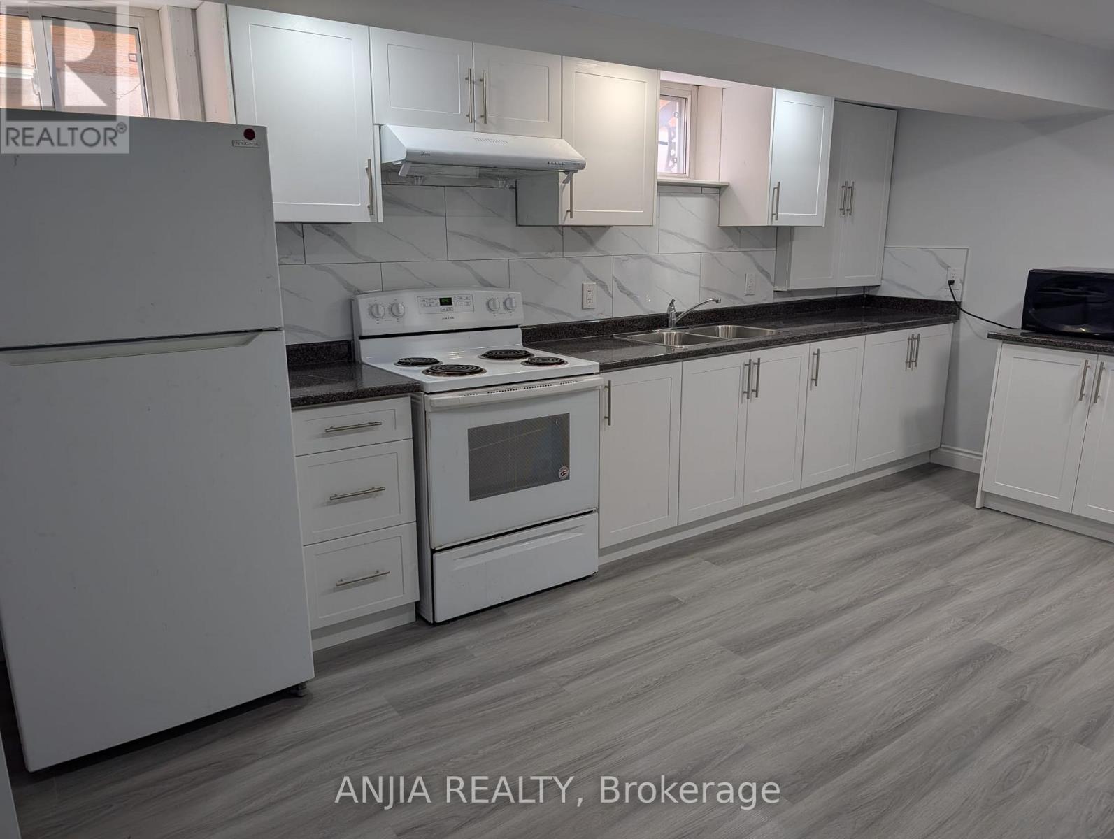 A kitchen with white cabinets and a white refrigerator.