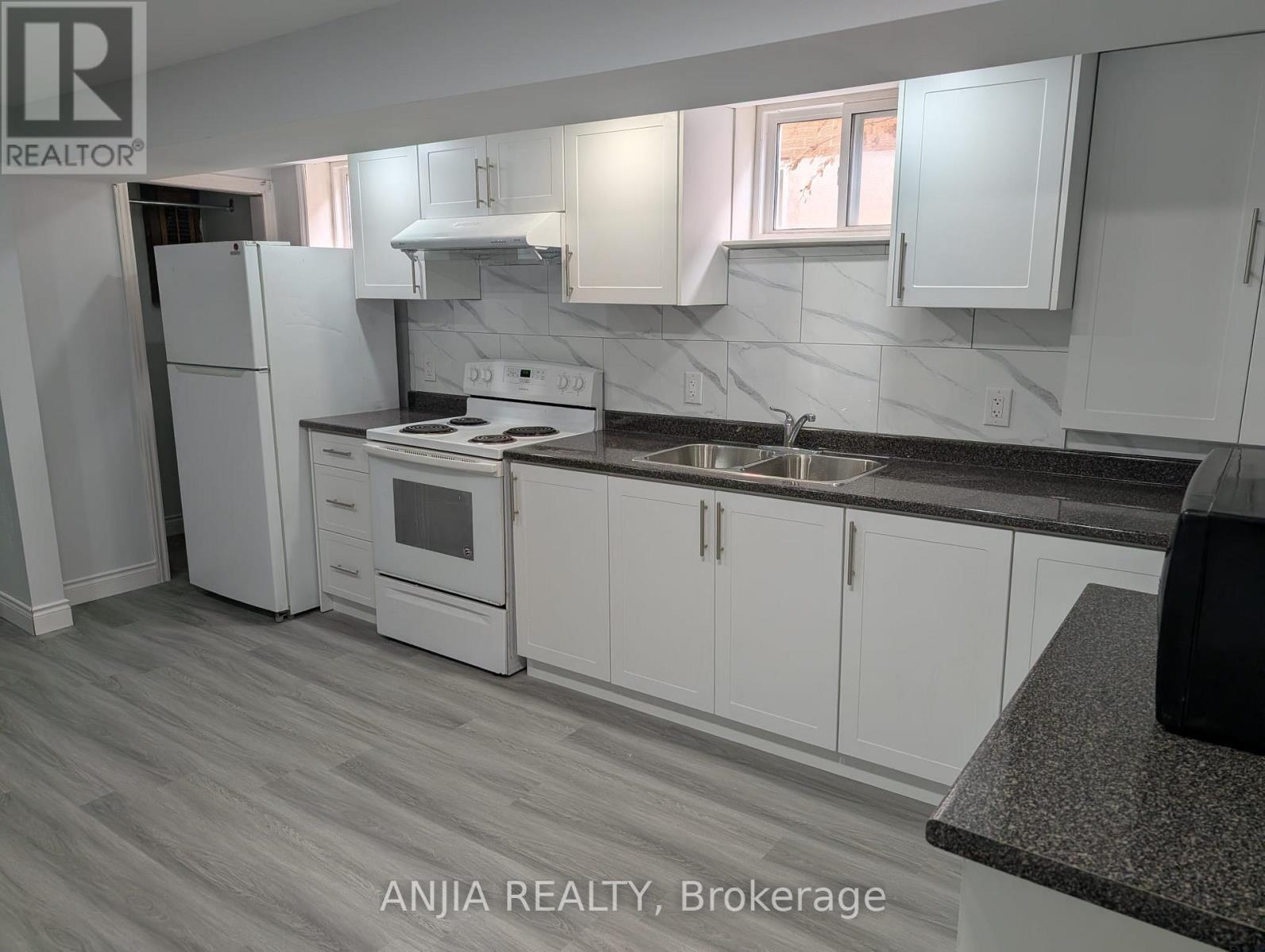 A kitchen with white cabinets and a black countertop.