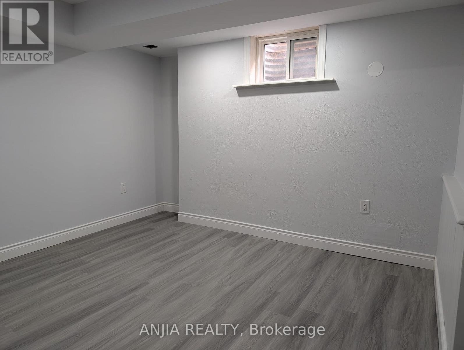 A room with a window and a wooden floor.