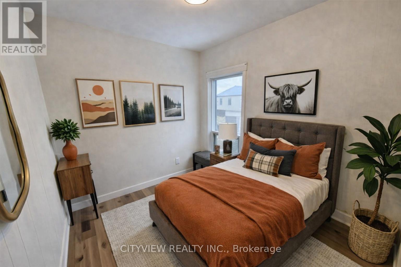 A bedroom with a bed, nightstand, and pictures on the wall.