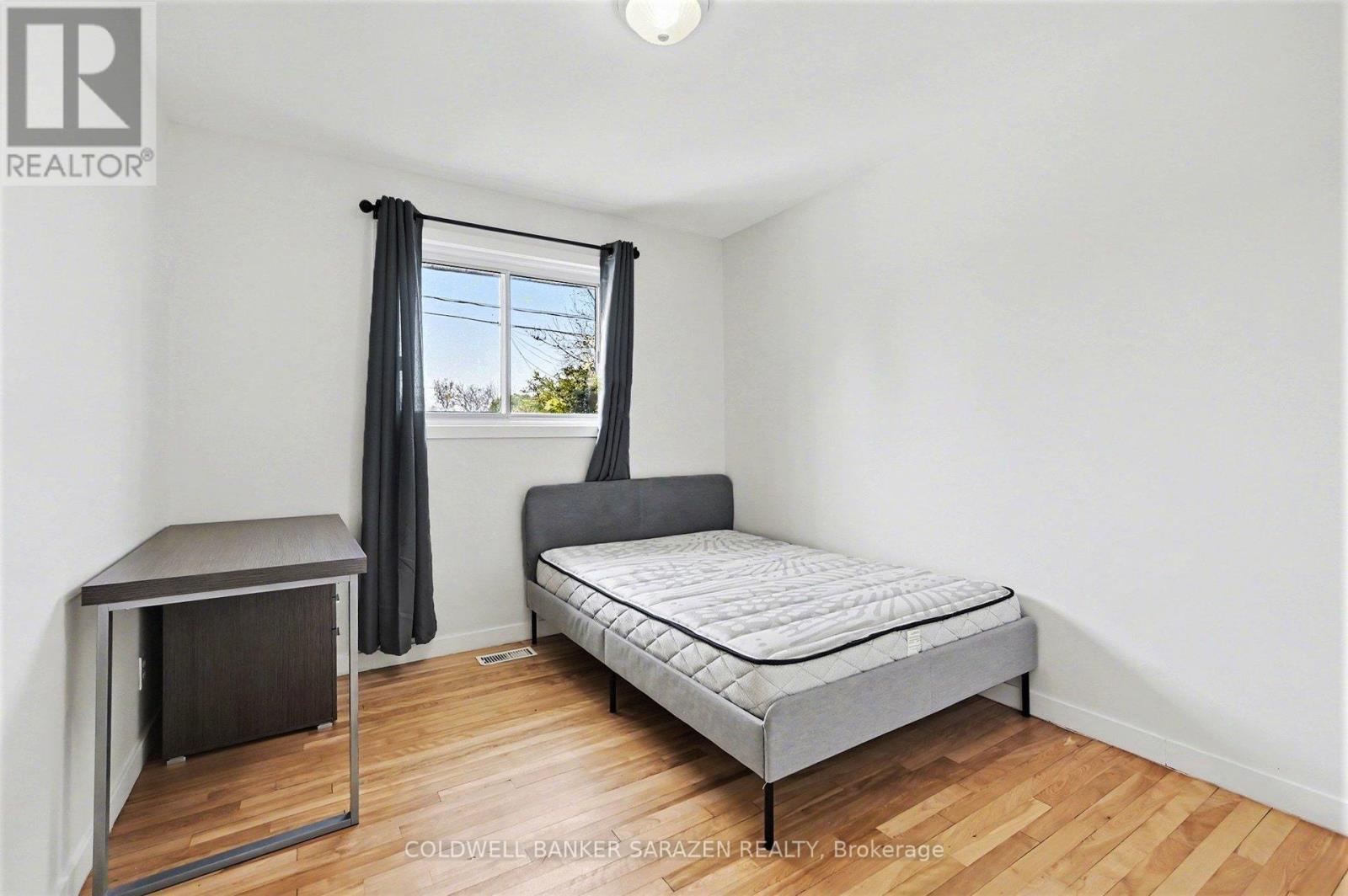 A bedroom with a bed, desk, and window.