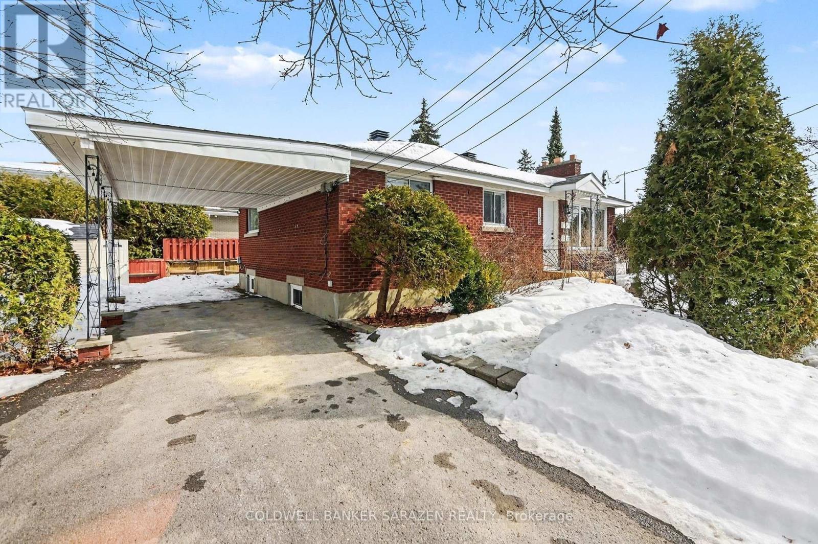 A house with a red brick exterior and a white roof is surrounded by snow.