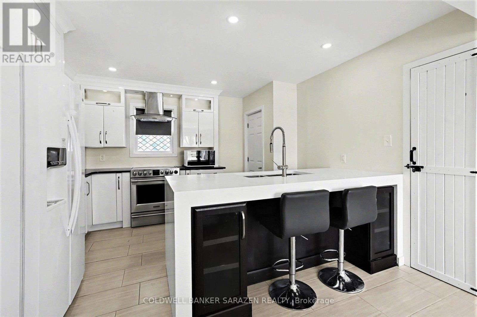 A modern kitchen with white cabinets and black bar stools.