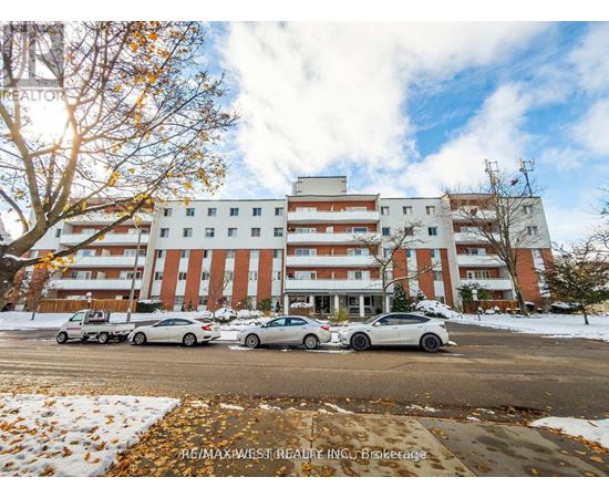 A large apartment building with cars parked in front.