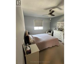 A bedroom with a bed, dresser, and window.