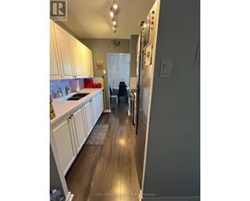 A kitchen with white cabinets and a wooden floor.