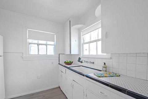A kitchen with white cabinets and a black and white checkered counter.