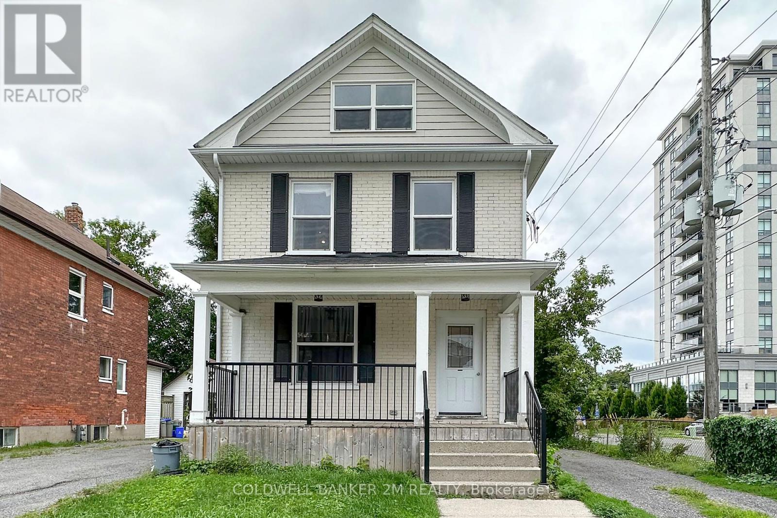 A two-story house with a porch and a fence in front.