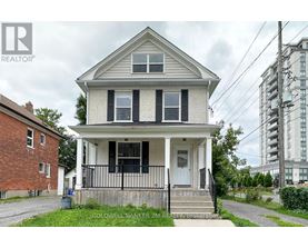 A two-story house with a porch and a fence in front.
