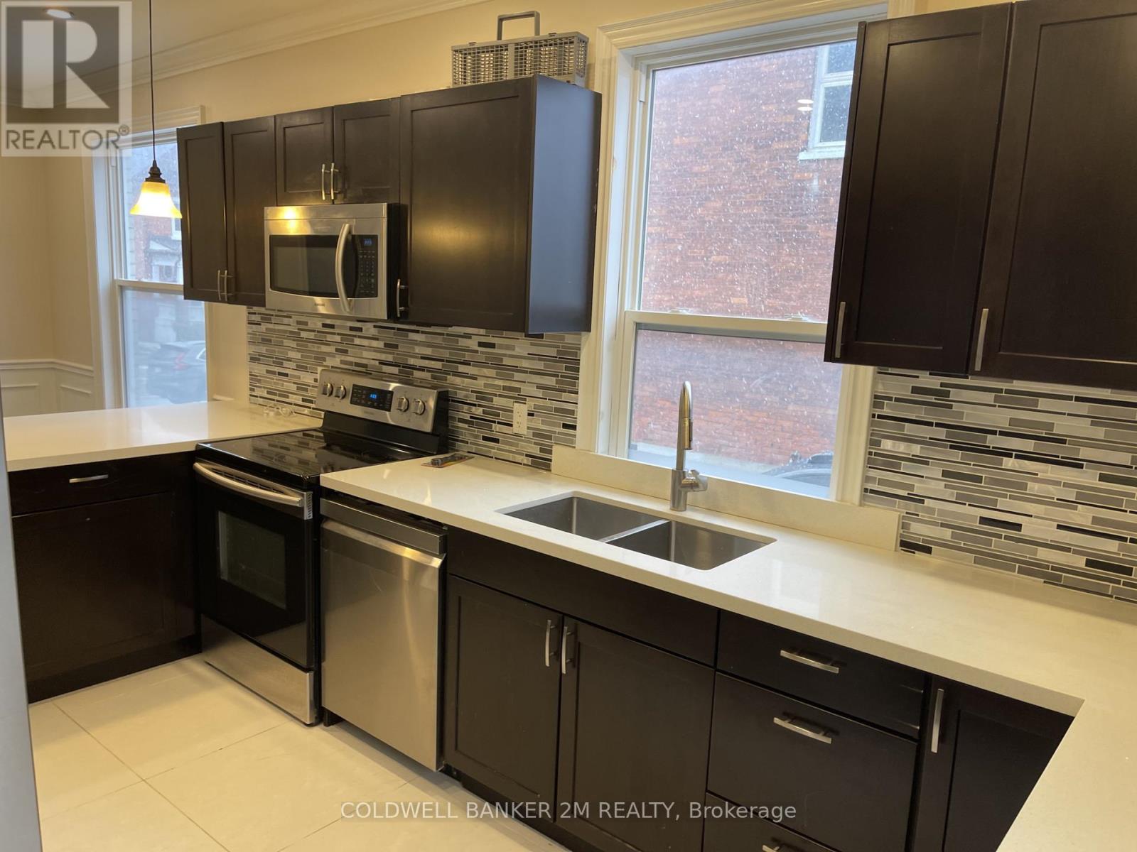 A kitchen with black cabinets and a stone backsplash.