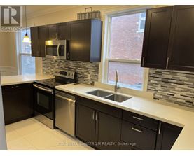 A kitchen with black cabinets and a stone backsplash.