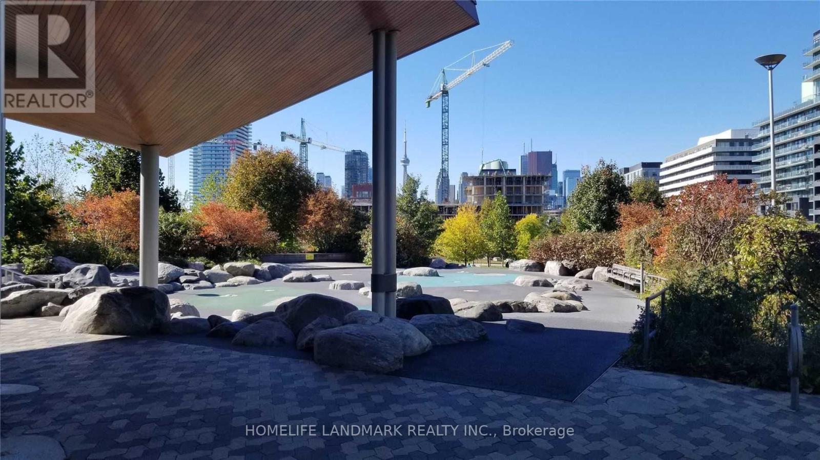 A real estate company's sign is displayed on a wooden structure overlooking a pool area.