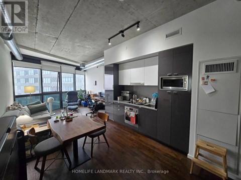 A modern kitchen with dark wood floors and a dining table with chairs.