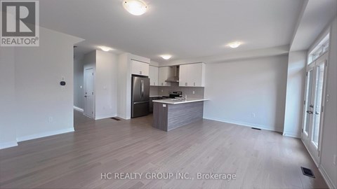 A spacious kitchen with white cabinets and a wooden floor.