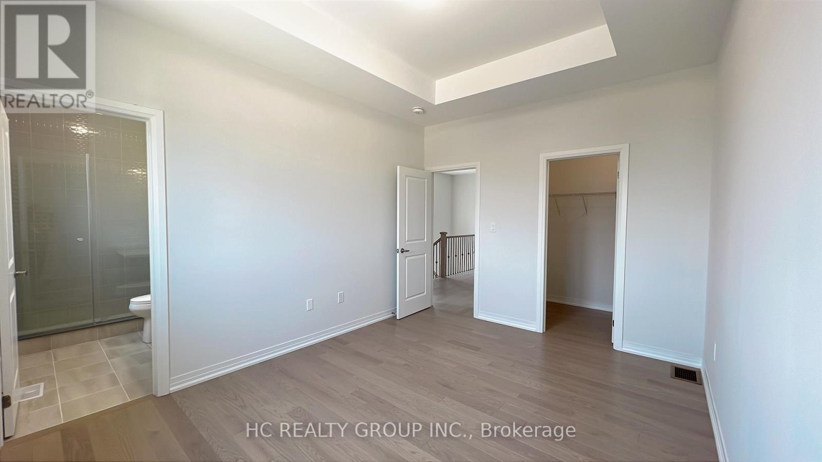A room with white walls and wooden flooring, with a glass door on the left and a white door on the right.