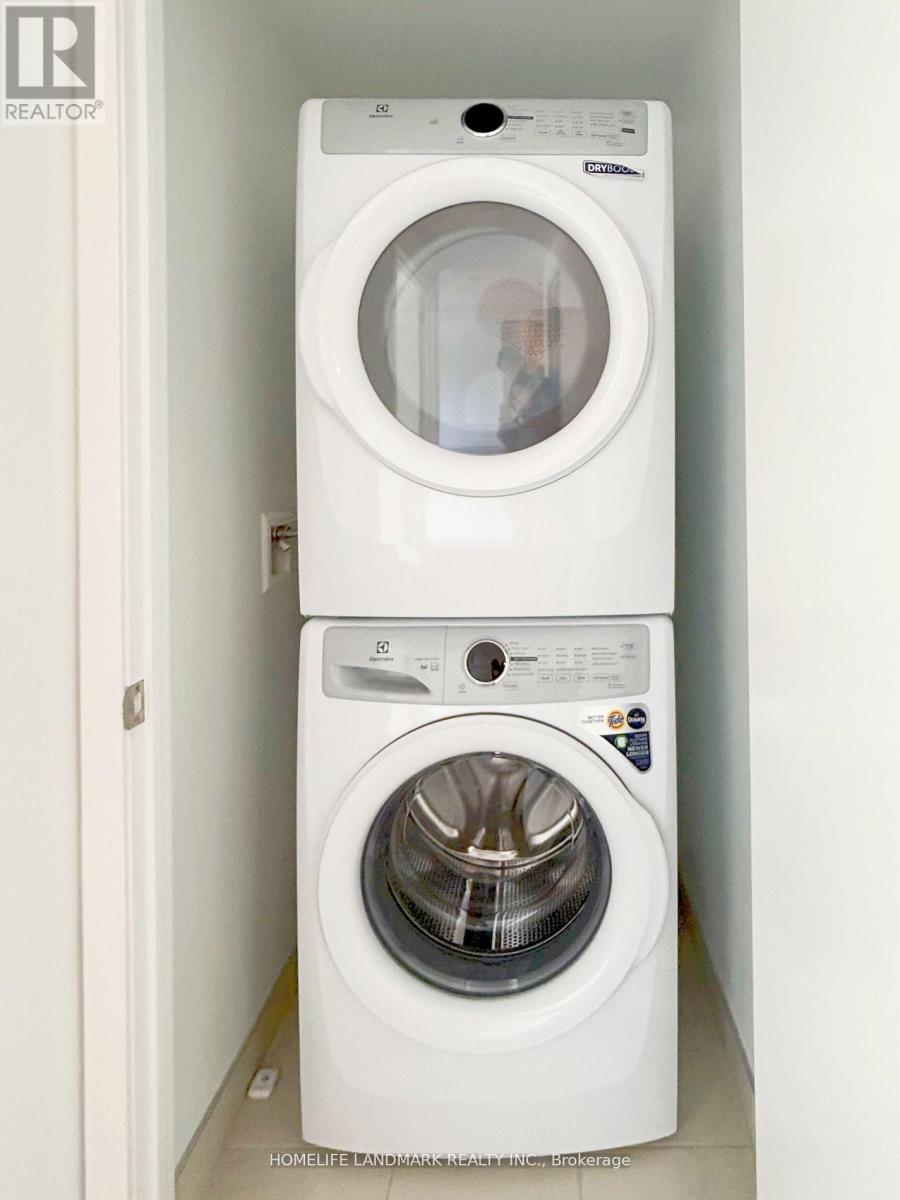 A white front load washing machine with a dryer on top is in a small space.
