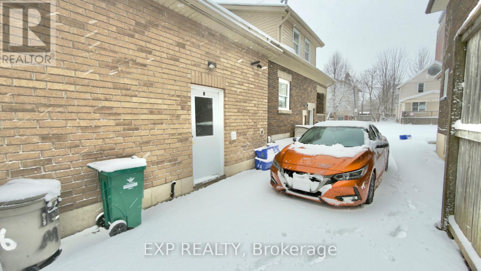 A car is parked in front of a brick building with a sign that says "REALTOR".